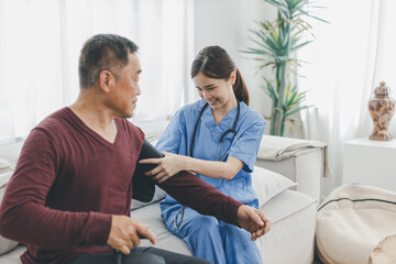 Obraz premium Caregiver nurse measuring blood pressure by using digital sphygmomanometer Senior patient at home. Caregiver nurse using medical device to measure blood pressure Senior patient