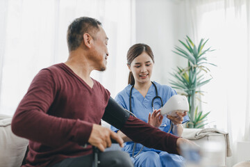 Obraz premium Caregiver nurse measuring blood pressure by using digital sphygmomanometer Senior patient at home. Caregiver nurse using medical device to measure blood pressure Senior patient