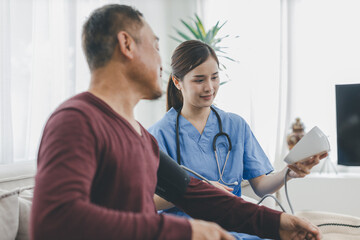 Caregiver nurse measuring blood pressure by using digital sphygmomanometer Senior patient at home....