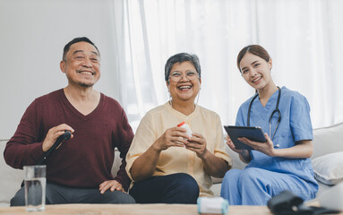 Nurse assisting her old patient at nursing home. Caregiver helping senior patient sit on sofa. Friendly female nurse talking with patient at nursing home
