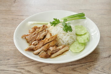 slice grilled chicken topping white sesame with Teriyaki Japanese sauce on rice in plate with cucumber and spring onion