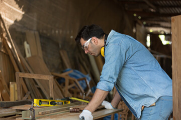 Male carpenter working at woodwork workshop. Male joiner working in furniture workshop