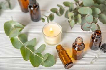 Eucalyptus essential oil in a glass bottle with green eucalyptus leaves on a textured wooden background. Aromatherapy concept. Spa. Natural organic ingredients for cosmetics and body care.Copy space
