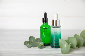 Eucalyptus essential oil in a glass bottle with green eucalyptus leaves on a textured wooden background. Aromatherapy concept. Spa. Natural organic ingredients for cosmetics and body care.Copy space