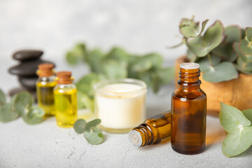 Eucalyptus essential oil in a glass bottle with green eucalyptus leaves on a textured wooden background. Aromatherapy concept. Spa. Natural organic ingredients for cosmetics and body care.Copy space