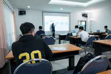 Rearview of adult students listening to lecturer in the classroom