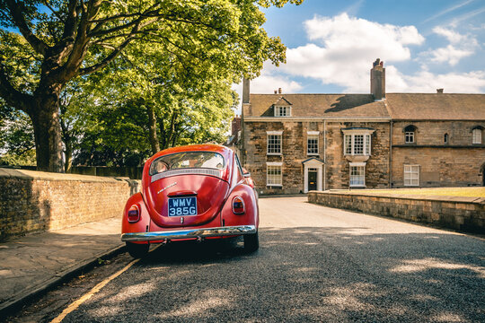 Lincoln - 01 July 2017 - Vintage Red VW Beetle with Traditional Stone Cottage in Lincoln, UK