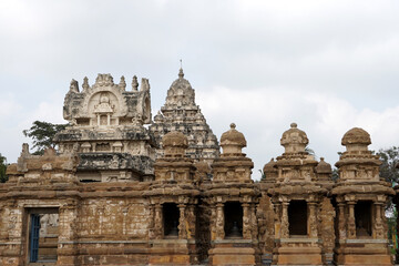 Fototapeta na wymiar Facade of ancient Kailasanathar temple. Historic Hindu Temple tower with sandstone carvings against cloudy background.