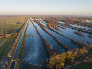 Ice skating on the canals in Holland. Winter day sunset and people on the ice. Aerial drone birds eye view.
