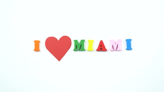 I love Miami. Text from colorful wooden letters and a beating paper red heart.