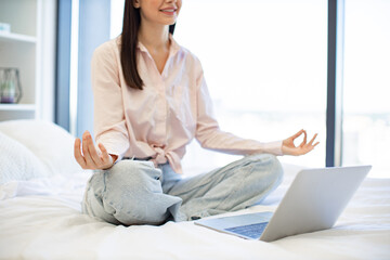 Cropped view of woman enjoying practicing yoga during break with modern laptop at home. Peaceful...