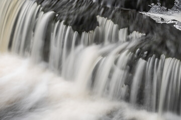 Winter, Bond Falls cascade captured with motion blur and framed by ice, Michigan's Upper Peninsula, USA