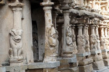 Fototapeta premium Row of pillars with carvings of Lion sculpture in in ancient Kanchi Kailasanathar temple in Kanchipuram, Tamil nadu. Indian art of Animal relief sculptures carved in sandstone at historic temple.