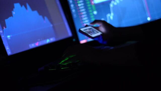 Trader works with computer. Screen with stock charts and data analysis. Stock market or crypto trading concept. Keyboard and smartphone 