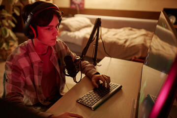 High angle portrait of teenage boy playing videogames at home with red neon light