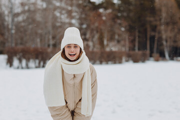 Obraz premium Happy smiling young woman portrait dressed coat scarf hat and mittens enjoys winter weather at snowy winter park