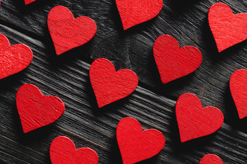 Red wooden hearts on black wooden background