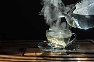 Glass cup of jasmine tea on wood table. Space for text