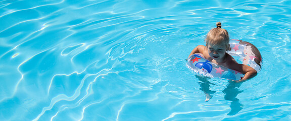 Child girl swims with an inflatable ring in the pool. Top view, flat lay. Banner