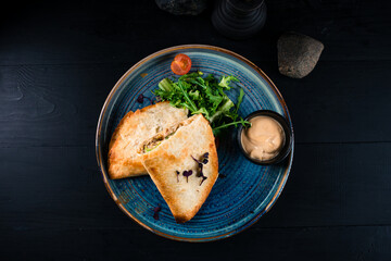Fried hot cheburek with chicken, onion, sauce and greens.