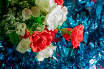 Bouquet of red and white artificial flowers on blue background. Selective focus