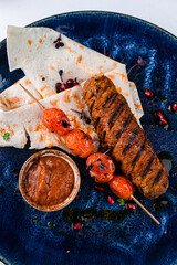 Hot marbled beef kebab with cherry tomatoes, sauce and pita bread.