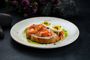 Italian breakfast bruschetta with salmon slices, cream cheese, greens, eggs and vegetable salad.