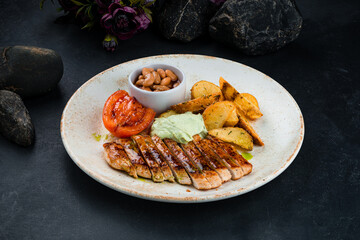 Dinner chicken fillet with rustic potato wedges, beans, tomatoes and sauce.