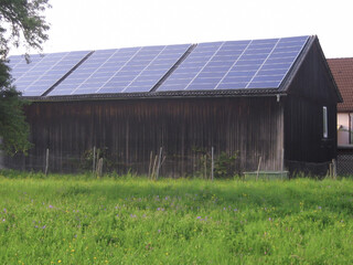 Fototapeta na wymiar Solar panels are installed on the roof of a private barn to collect solar energy. Renewable green energy and nature conservation