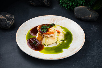 Fried chicken fillet with mashed potatoes, cheese, tomatoes, greens and sauce in plate.