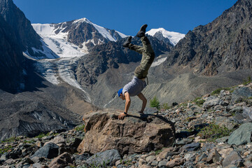 Man handstand against the background of hight mountains, snowy peaks and glacier. Sports and...