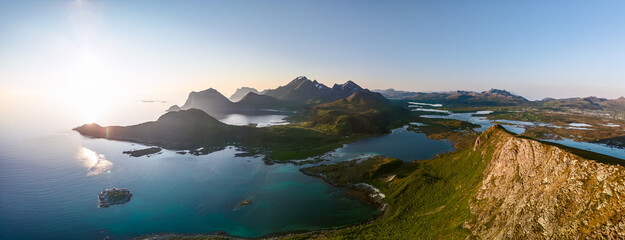 A radiant midnight sun crowns the serene panorama at Offersoykammen, with Nappstraumen's intricate...