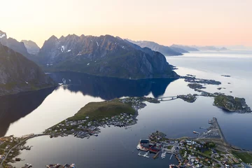 Fotobehang Aerial view of the serene Reine village in Lofoten, Norway under the midnight sun, with mountain reflections on calm waters, bridged islands © Artem