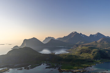 As the midnight sun descends over Lofoten, the silhouette of Offersoykammen stands against the soft...