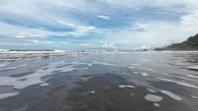 An idyllic beach video - gentle waves breaking in front of the camera, surrounded by bright blue skies and picturesque clouds. A perfect place to enjoy the beauty of nature. Copy space