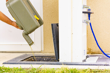 Man emptying caravan tank toilet cassette in dump station.