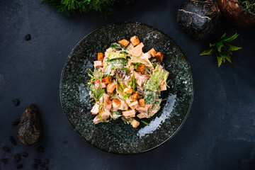 Green salad with sweet pepper, cucumbers, lettuce, tomatoes, arugula, croutons and sauce in plate.