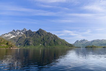 Calm waters mirror the dramatic mountain scenery of Lofoten, Norway, bathed in the light of a...