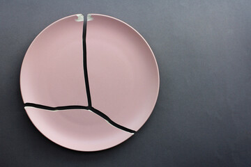 A broken pink ceramic plate on a gray background. view from above. The concept of diet, old things