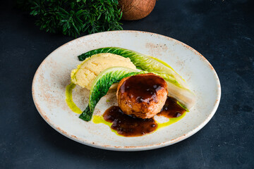 Portion chicken cutlet with mashed potatoes, greens and sauce on table.