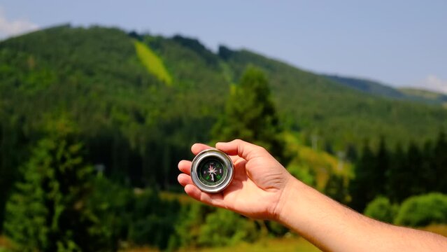 a man holds a compass in his hands against the backdrop of mountains. Selective focus.