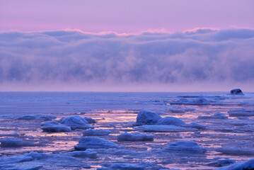 Frozen winter seascape with sea smoke in the distance in Helsinki, Finland.