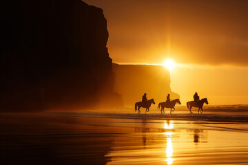 Group of people riding horses in beautiful Irish landscape on dramatic sunset. Tourists admiring...