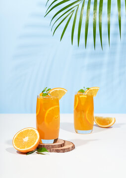 Glass of 100% Orange juice with orange slices fruits on pastel color background. Summer sea vacation and travel concept. Exotic summer drinks.