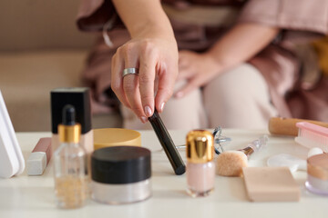 Closeup image of girl taking mascara from table