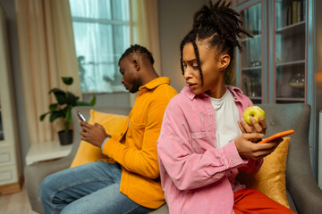 Portrait of pensive attractive African American woman sitting next to young man on sofa at home