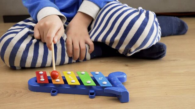 Adorable hispanic toddler playing xylophone sitting at home