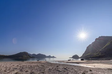 Foto op Aluminium Bright sunburst over the serene Haukland Beach in Lofoten, Norway, with clear blue skies and mountain backdrop © Artem