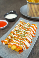 stik kentang keju or fried cheese potato sticks served with chili sauce, mayonnaise and a sprinkle of dried parsley