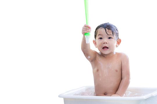 Toddler Playing with Water in Bath Time Fun. Cheerful Asian Baby Boy enjoying teke a shower, playfully lifting a water toy, splashing and having fun with water droplets in the air. Child aged 3 years.